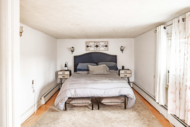 bedroom featuring hardwood / wood-style flooring and a baseboard heating unit