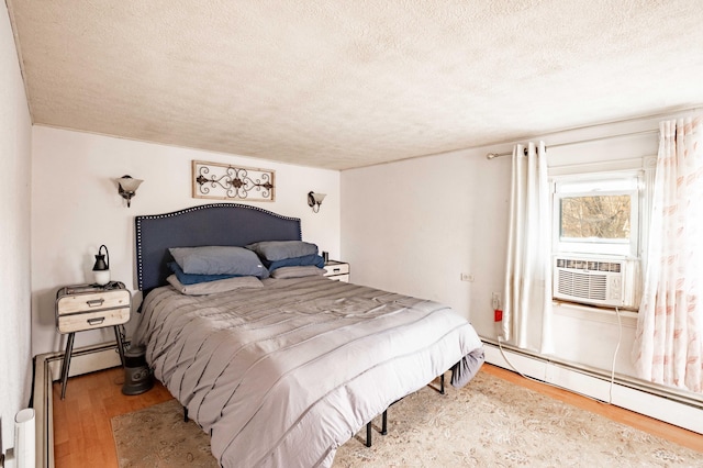 bedroom featuring a textured ceiling, hardwood / wood-style flooring, and a baseboard heating unit