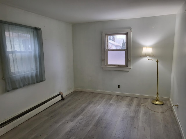 empty room with light wood-type flooring and a baseboard heating unit