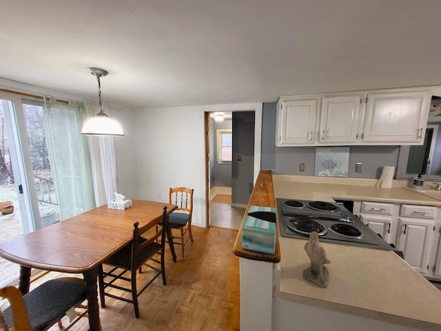 kitchen featuring white cabinets, decorative light fixtures, cooktop, and light parquet floors