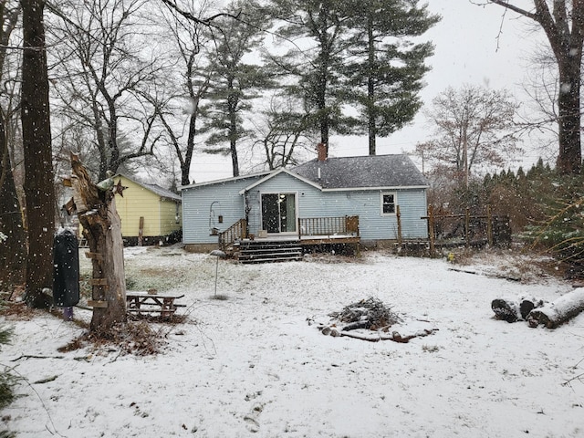 snow covered back of property with a deck