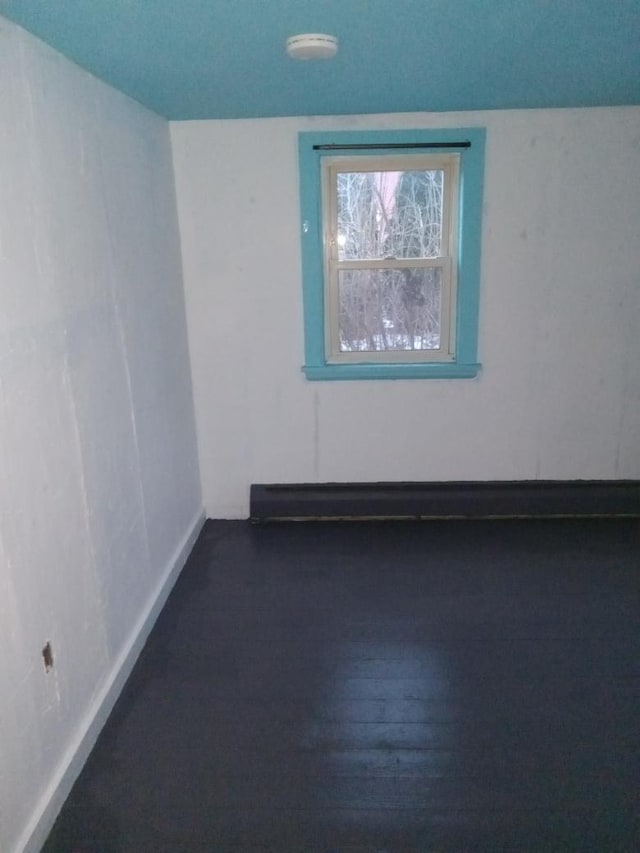 spare room featuring dark wood-type flooring and a baseboard radiator