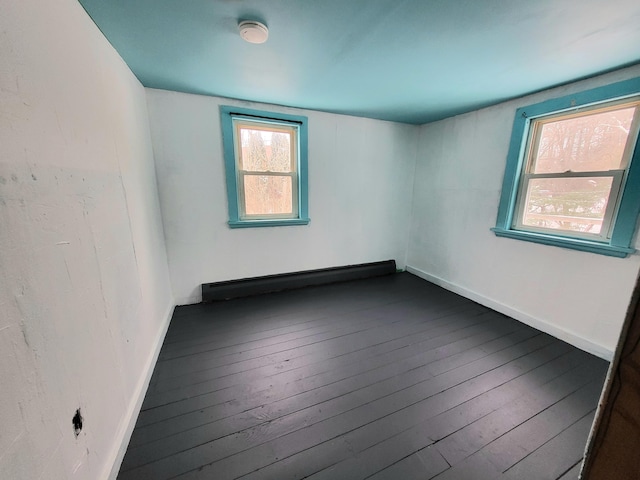 unfurnished room with plenty of natural light, baseboard heating, and dark wood-type flooring