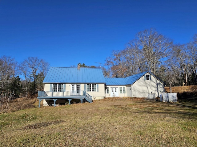 rear view of property with metal roof, a deck, central AC, and a lawn