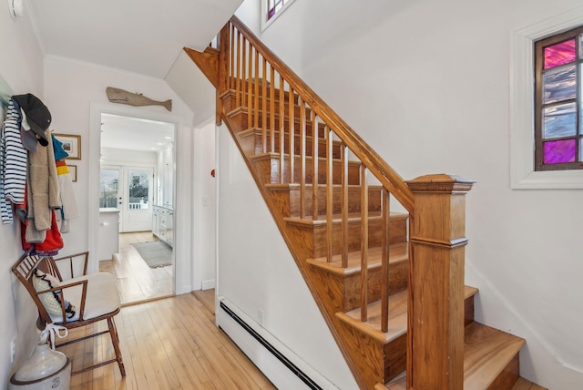 stairway with baseboard heating, french doors, crown molding, and hardwood / wood-style floors