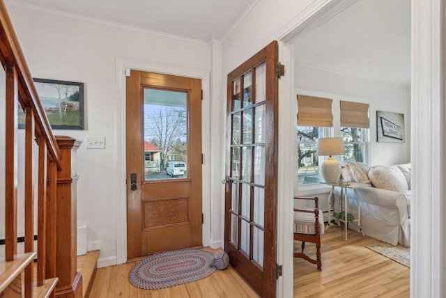 entryway with stairs, crown molding, baseboards, and light wood finished floors