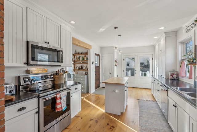 kitchen featuring hanging light fixtures, french doors, light wood-style floors, appliances with stainless steel finishes, and wood counters