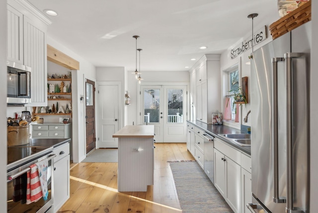 kitchen with light wood finished floors, white cabinetry, stainless steel appliances, and a sink