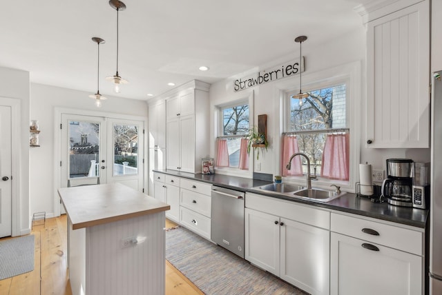 kitchen featuring light wood-style flooring, a sink, french doors, dishwasher, and a center island