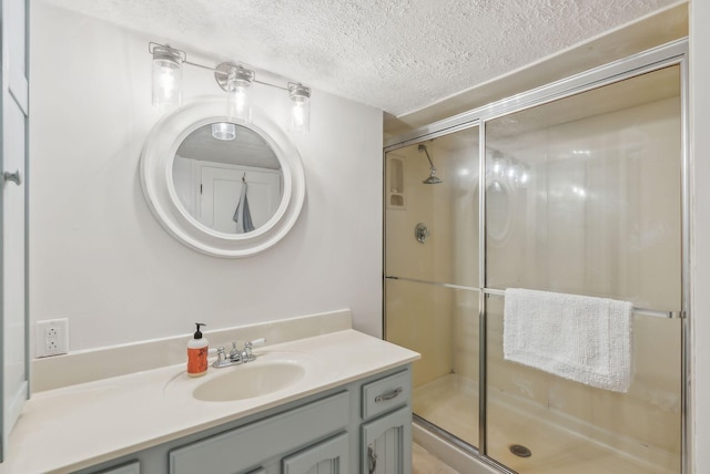 full bathroom with a shower stall, a textured ceiling, and vanity