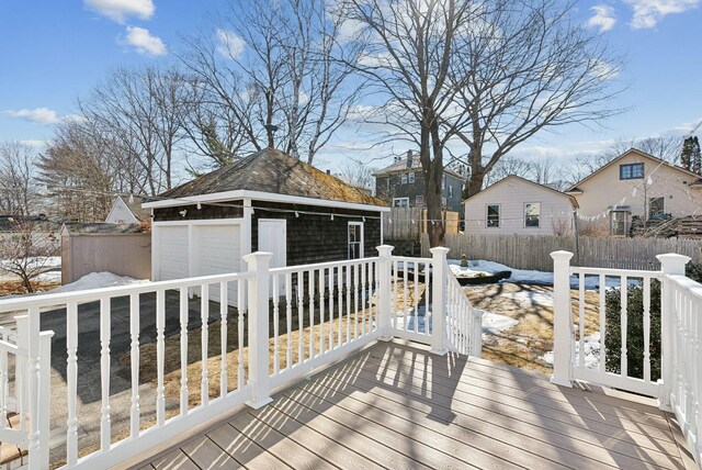 wooden deck featuring an outdoor structure, fence, and a garage