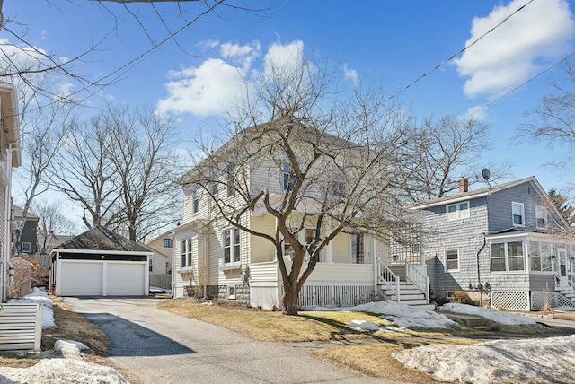 american foursquare style home with an outdoor structure, a detached garage, a sunroom, and a chimney