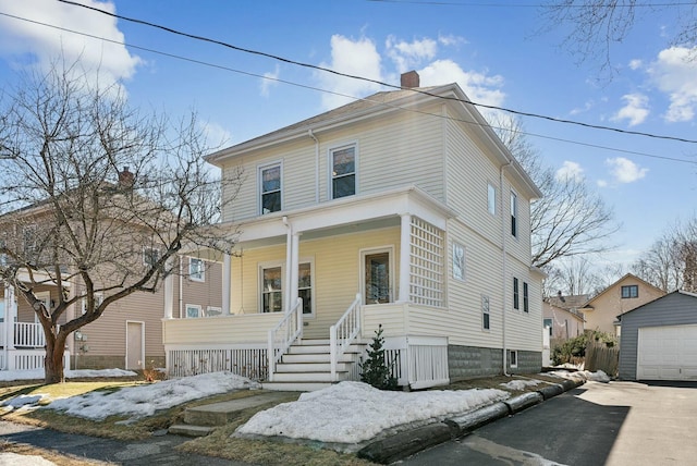 american foursquare style home with a detached garage, covered porch, a chimney, an outdoor structure, and driveway