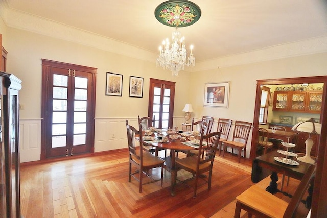 dining space with plenty of natural light, an inviting chandelier, crown molding, and french doors