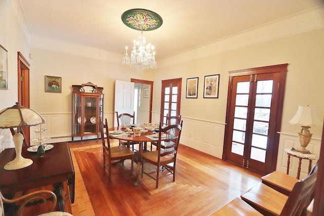 dining room with french doors, an inviting chandelier, wood-type flooring, and ornamental molding