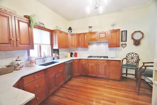 kitchen featuring decorative backsplash, appliances with stainless steel finishes, sink, hardwood / wood-style flooring, and a chandelier