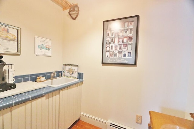 bathroom featuring sink, hardwood / wood-style floors, and a baseboard heating unit