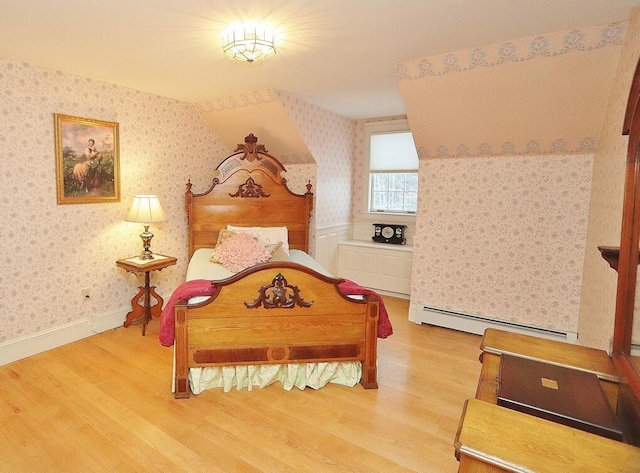 bedroom with wood-type flooring and a baseboard heating unit