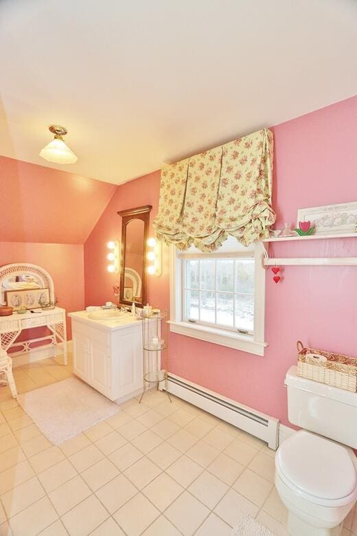 bathroom with a baseboard radiator, tile patterned floors, vaulted ceiling, toilet, and vanity