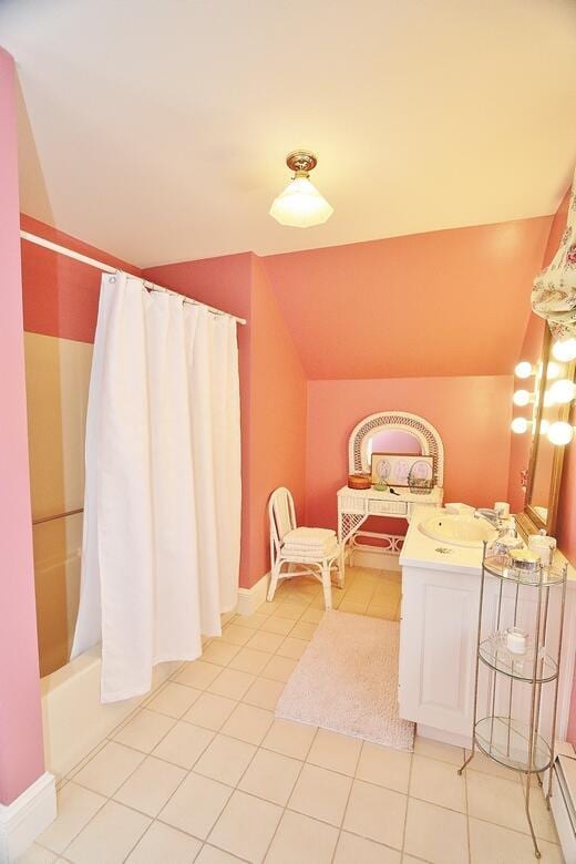 bathroom with tile patterned flooring, vanity, shower / bathtub combination with curtain, and lofted ceiling