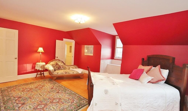 bedroom with hardwood / wood-style floors and lofted ceiling