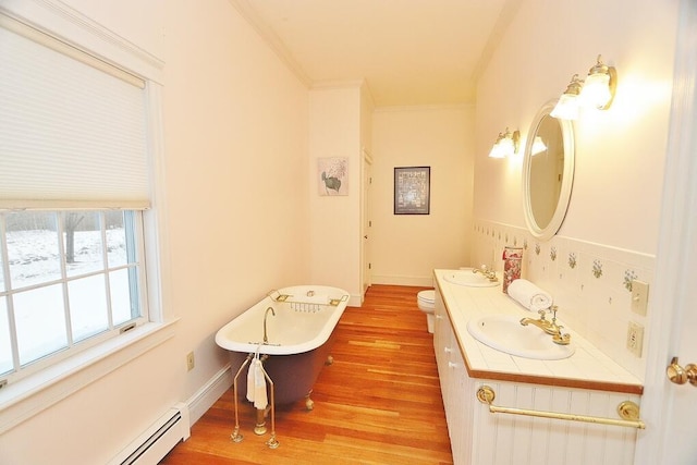 bathroom with hardwood / wood-style floors, a bathing tub, crown molding, toilet, and baseboard heating