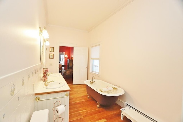 bathroom with ornamental molding, vanity, a baseboard radiator, hardwood / wood-style floors, and a tub