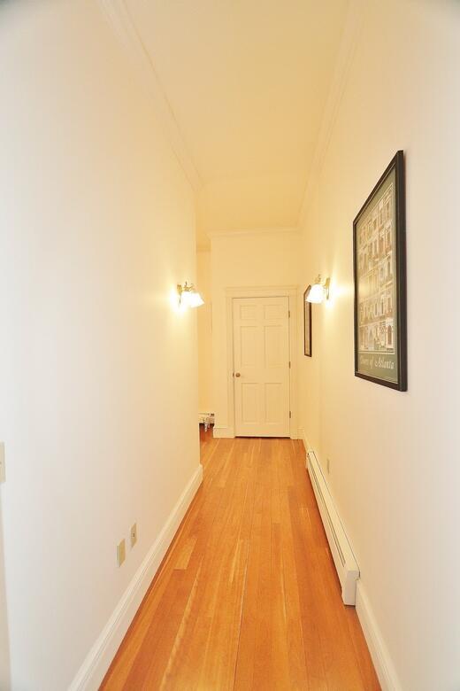 corridor with hardwood / wood-style floors, baseboard heating, and crown molding