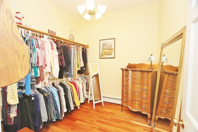 spacious closet featuring wood-type flooring, a baseboard radiator, and a notable chandelier