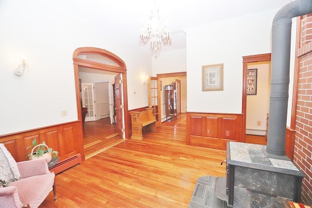 corridor featuring hardwood / wood-style flooring, ornamental molding, a baseboard radiator, and a chandelier