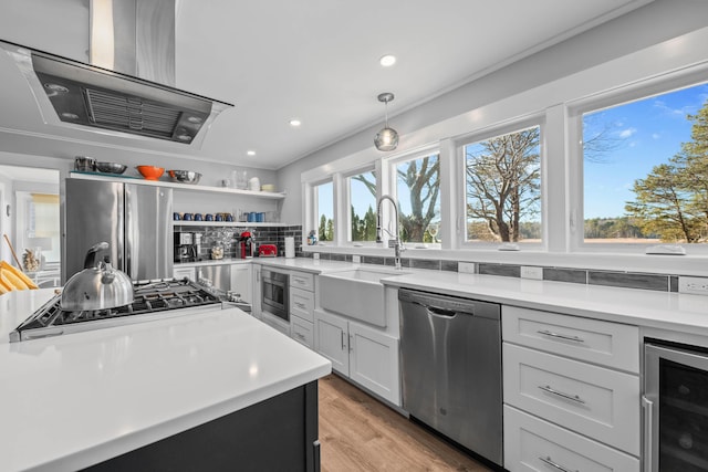 kitchen featuring decorative backsplash, stainless steel appliances, white cabinetry, wine cooler, and hanging light fixtures