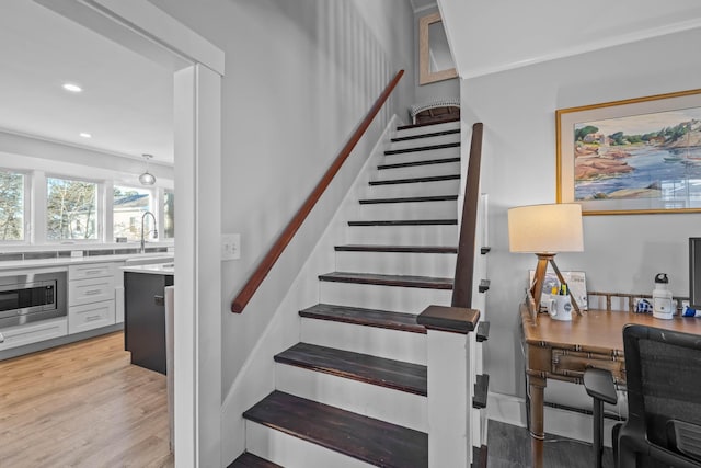 staircase featuring wood-type flooring and sink