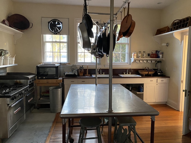 399 Hermits Point Rd, Islesboro, ME 04848 - kitchen with open shelves, dark countertops, a sink, white cabinetry, and light wood-type flooring