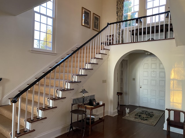 399 Hermits Point Rd, Islesboro, ME 04848 - staircase featuring a high ceiling, a wealth of natural light, baseboards, and wood finished floors