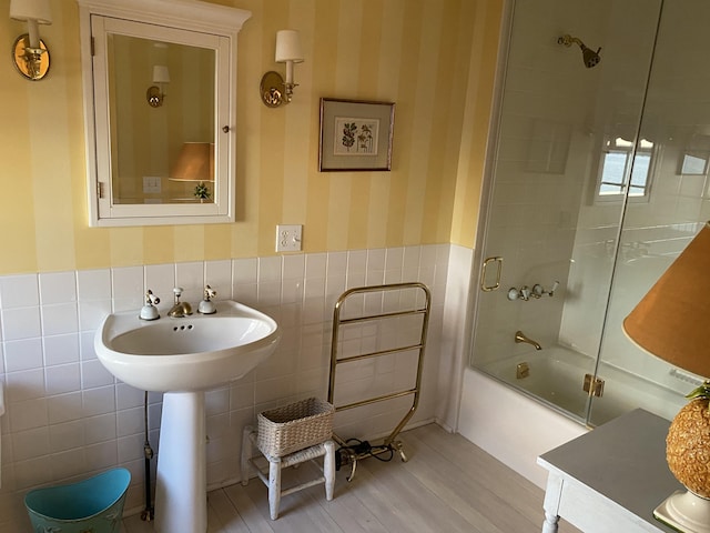 399 Hermits Point Rd, Islesboro, ME 04848 - full bath with wainscoting, wood finished floors, tile walls, wallpapered walls, and bath / shower combo with glass door
