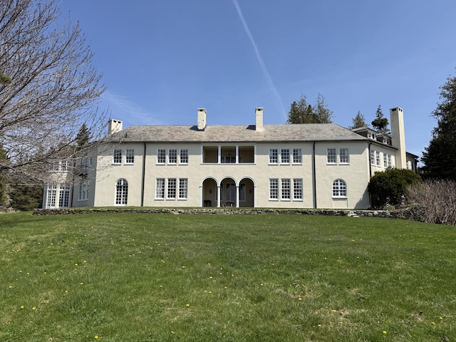 399 Hermits Point Rd, Islesboro, ME 04848 - back of house featuring a lawn, a chimney, stucco siding, and a balcony