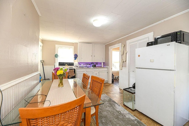 kitchen with white cabinetry, crown molding, white appliances, and tile patterned flooring