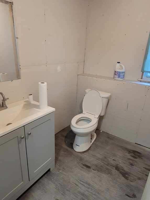 half bathroom featuring toilet, vanity, and wood finished floors