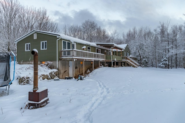 snow covered property featuring a trampoline and a deck