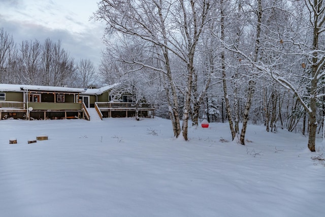 yard layered in snow featuring a deck