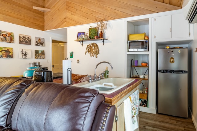 kitchen with appliances with stainless steel finishes, a wall mounted AC, sink, dark hardwood / wood-style floors, and white cabinetry