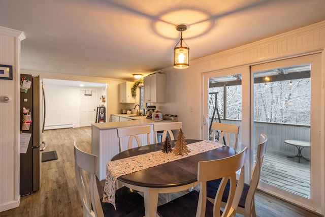 dining space with wood-type flooring, a baseboard heating unit, and sink