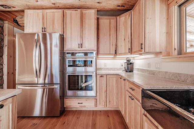 kitchen featuring light wood-type flooring, light brown cabinetry, and appliances with stainless steel finishes