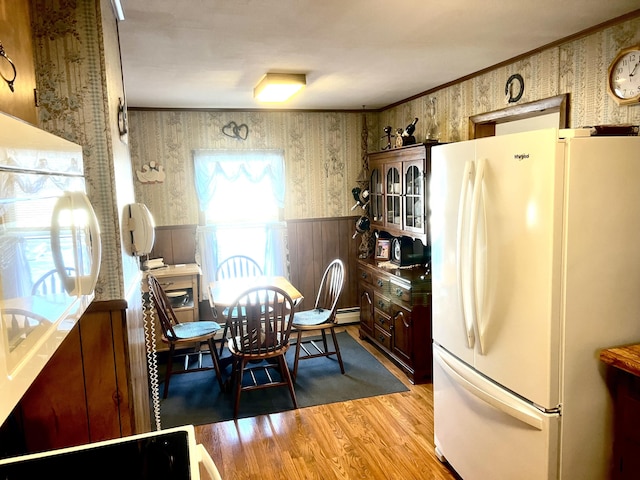 dining room with wooden walls, plenty of natural light, light hardwood / wood-style floors, and ornamental molding