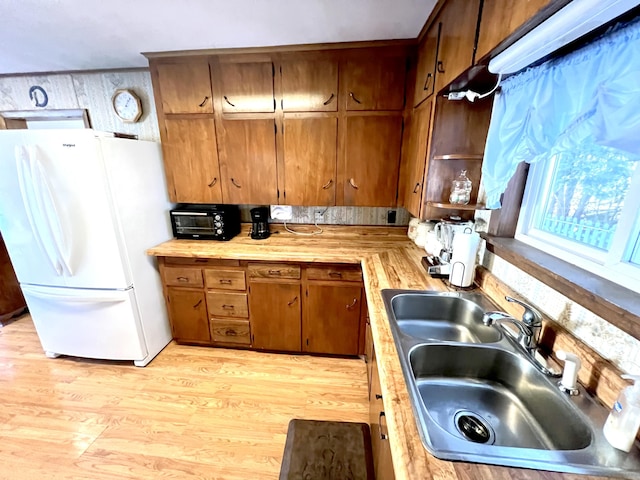 kitchen with light hardwood / wood-style flooring, white fridge, and sink