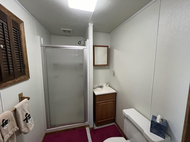 bathroom featuring vanity, a shower with shower door, and toilet