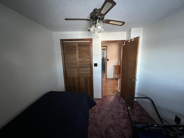 carpeted bedroom featuring ceiling fan, a textured ceiling, and a closet