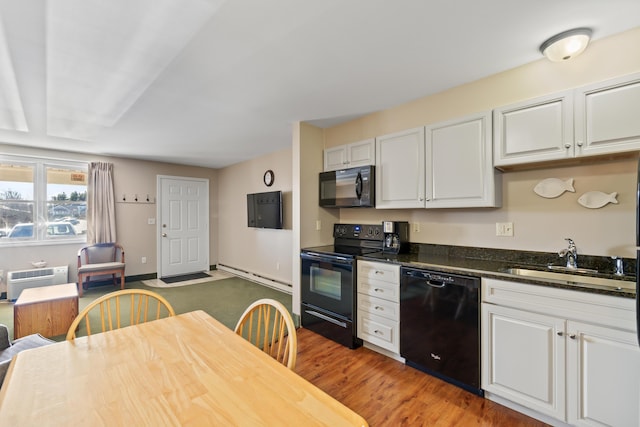 kitchen featuring sink, a wall mounted AC, black appliances, white cabinets, and a baseboard radiator