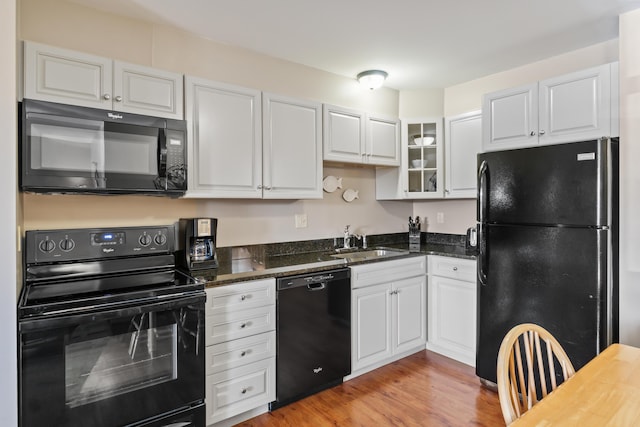 kitchen featuring white cabinetry, sink, dark stone countertops, and black appliances