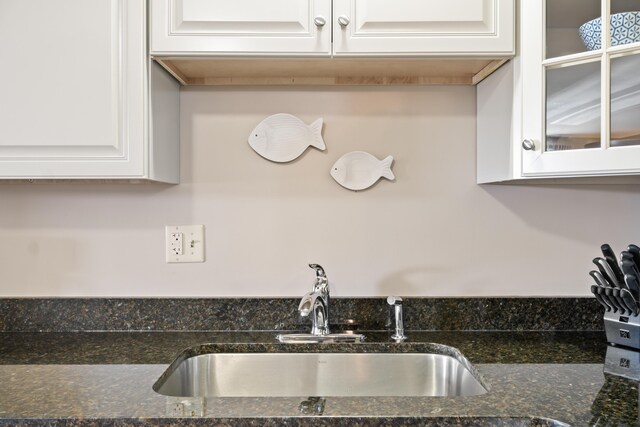 kitchen with white cabinetry, sink, and dark stone countertops